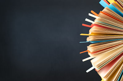 A rotating card index, filled with cards and divided with multicoloured tabs. cropped at right side of frame. A black chalkboard background provides copy space to the left.