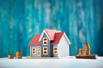 Red house model on wooden background with banknotes and coins