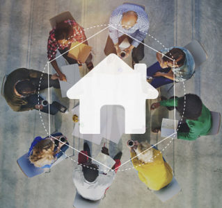 A group of people connected around the image of a house.