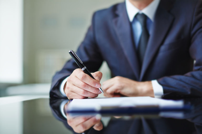 Businessman sitting at office desk and signing a contract