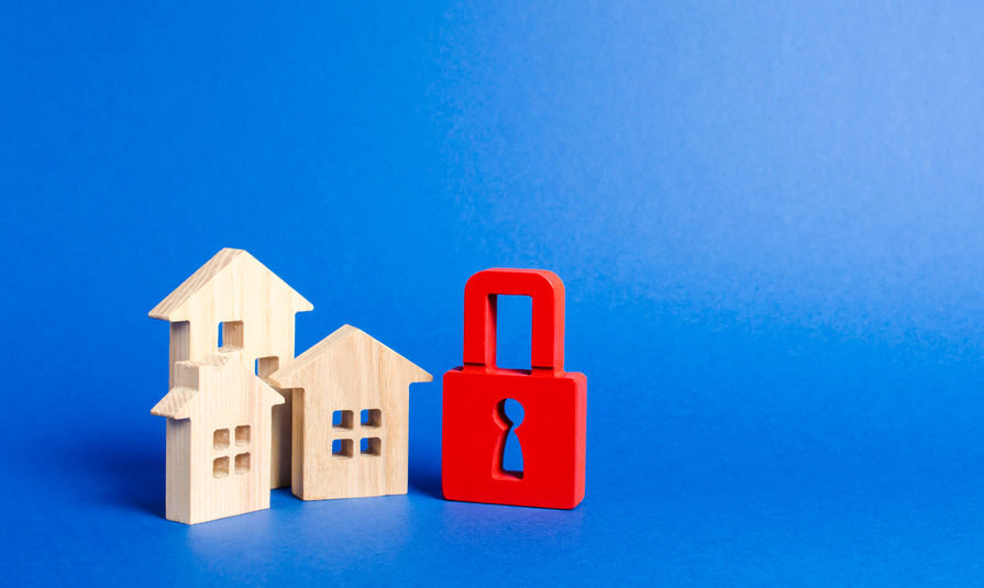Three houses and a red padlock. Unavailable and expensive real estate. house Insurance. Security and safety. Confiscation for debts. alarm system. seizure of property. Protection of property rights.