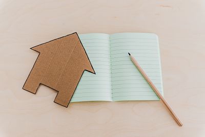 cardboard cut out of house with pencil and notebook