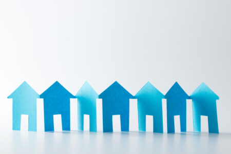 Blue paper houses in a row on white background