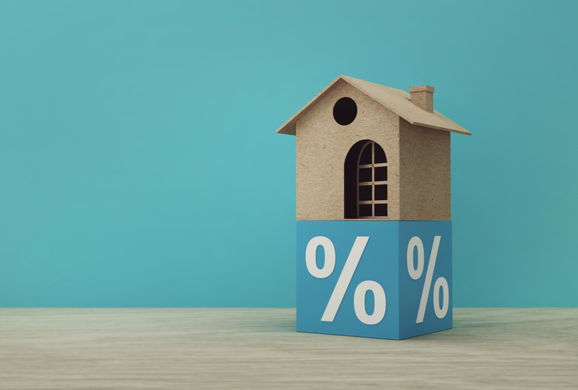 Creative idea of house model paper and percentage blue block on wooden table. Property investment real estate and house mortgage financial concept.