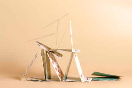 Crashed house of cards. Falling cards on beige background