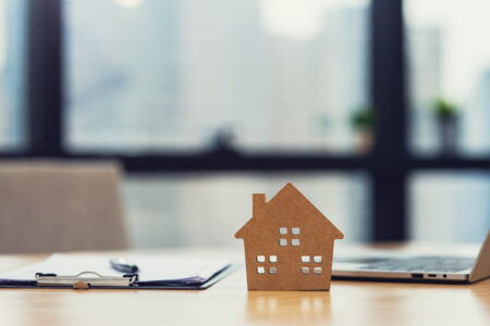 Home model put near Lease or Rental agreement document and laptop with copy space, real estate Business for buy , loan or investment concept