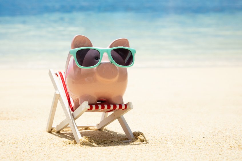 A money bank on a beach representing saving for short term rental properties