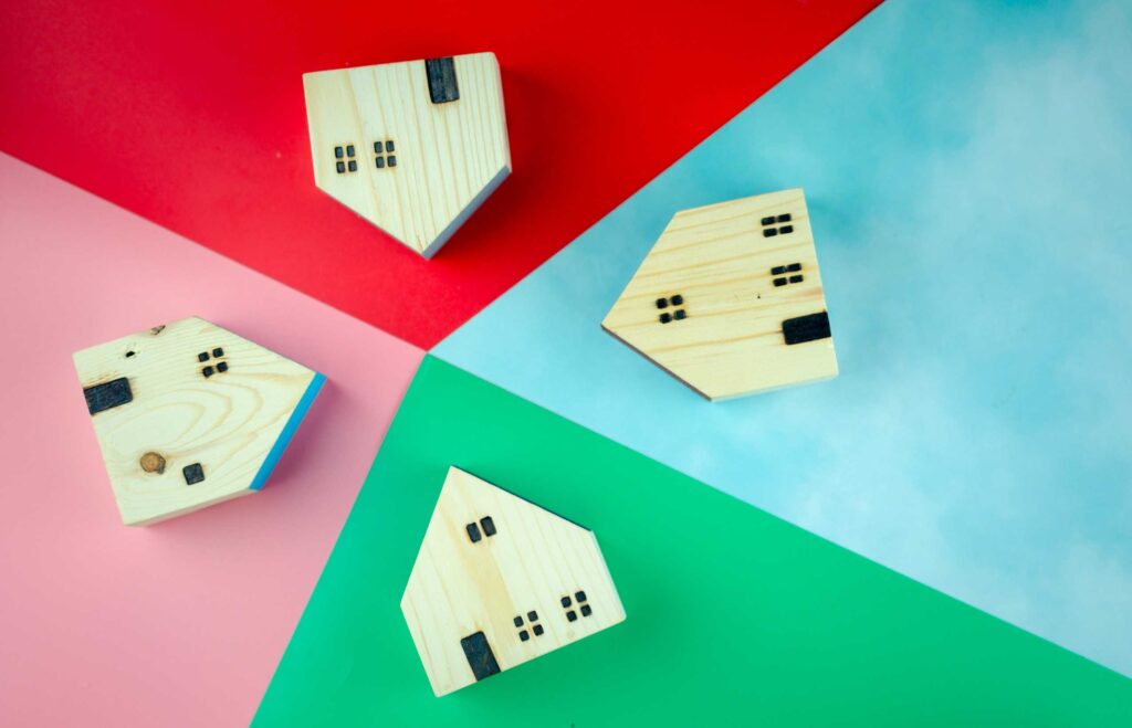 Four wooden house models arranged with different coloured backgrounds to represent short term lettings.
