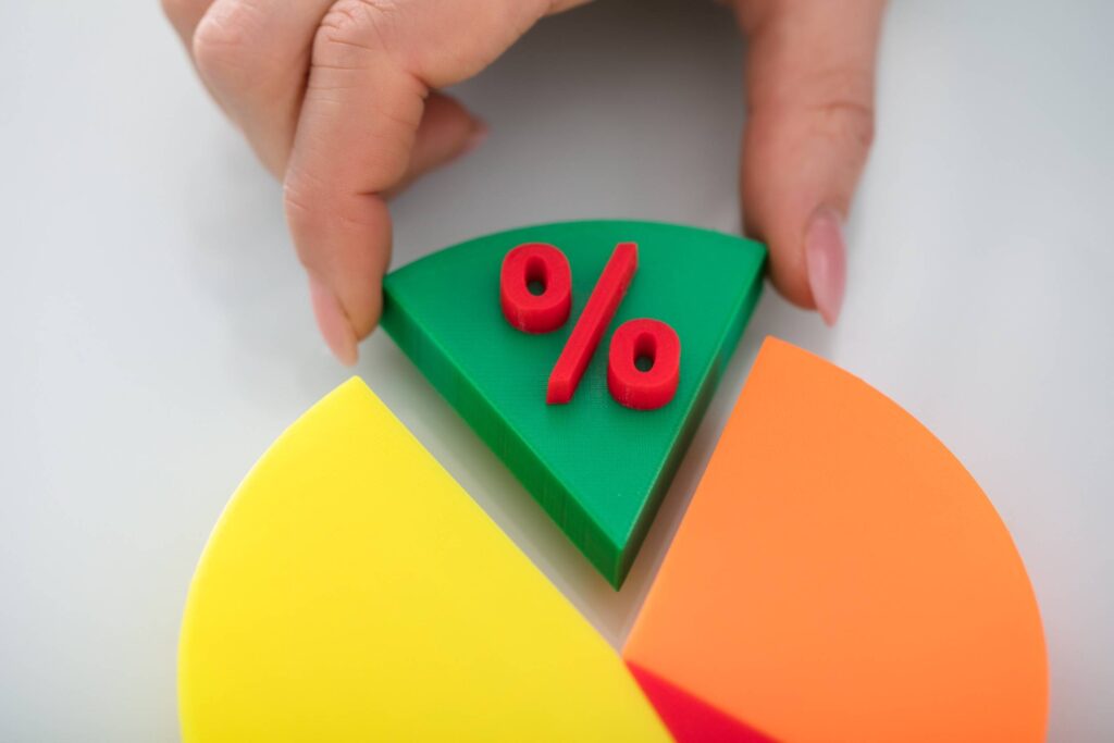 Close-up Of A Person's Finger Taking Green Piece Of Pie Chart With Red Percentage Symbol