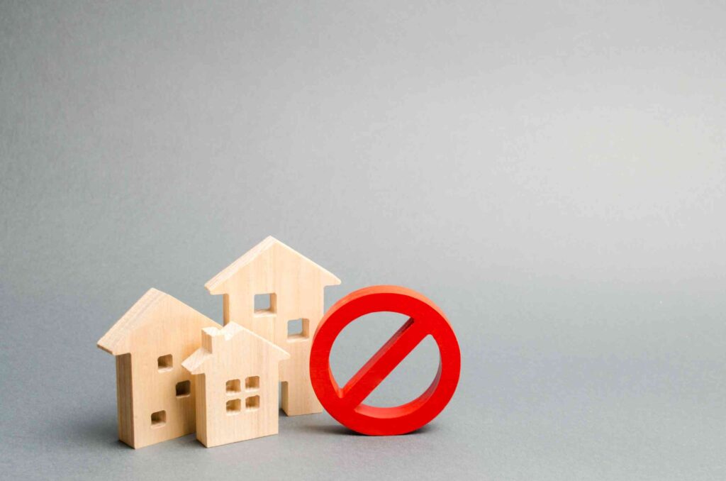 No Sign and wooden houses on an gray background symbolising eviction.