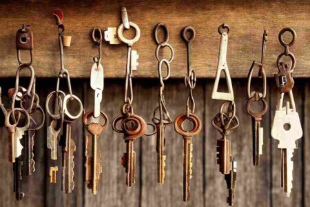 Old keys hanging on a wooden panel to symbolise lock changes.