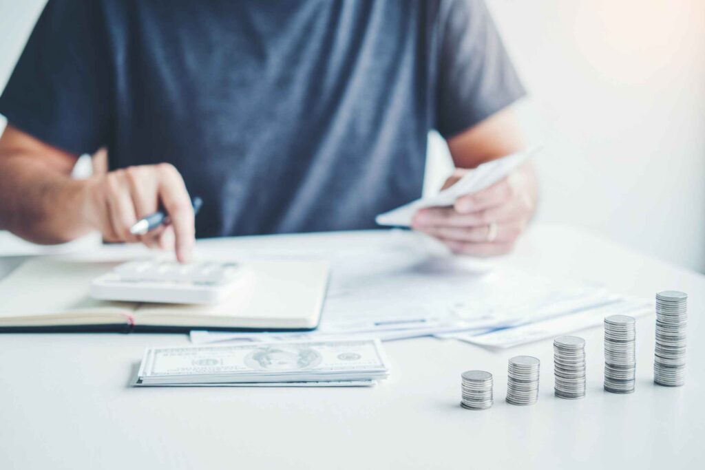 A man using a calculator while counting money representing MTD for ITSA