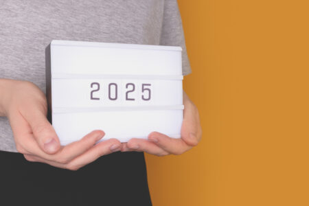 Hands hold lightbox with 2025 numbers in front of yellow background. New Year concept with plce for text.