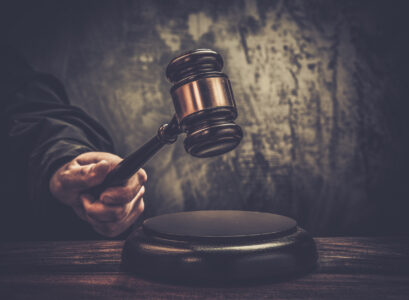 Judge's hand holding wooden hammer