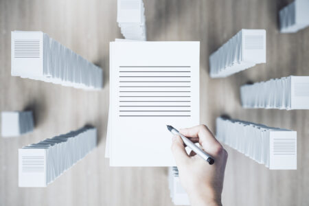Top view of hand with paperwork stack on wooden background. Workload and bureaucracy concept