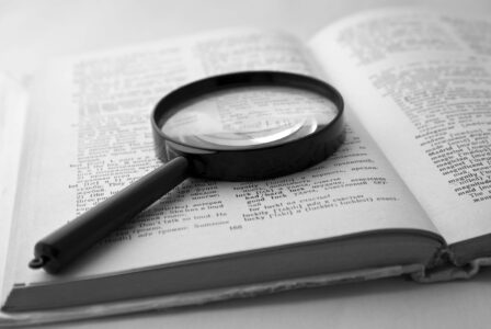 Magnifier on the open page of the English-Russian dictionary. The black-and-white image